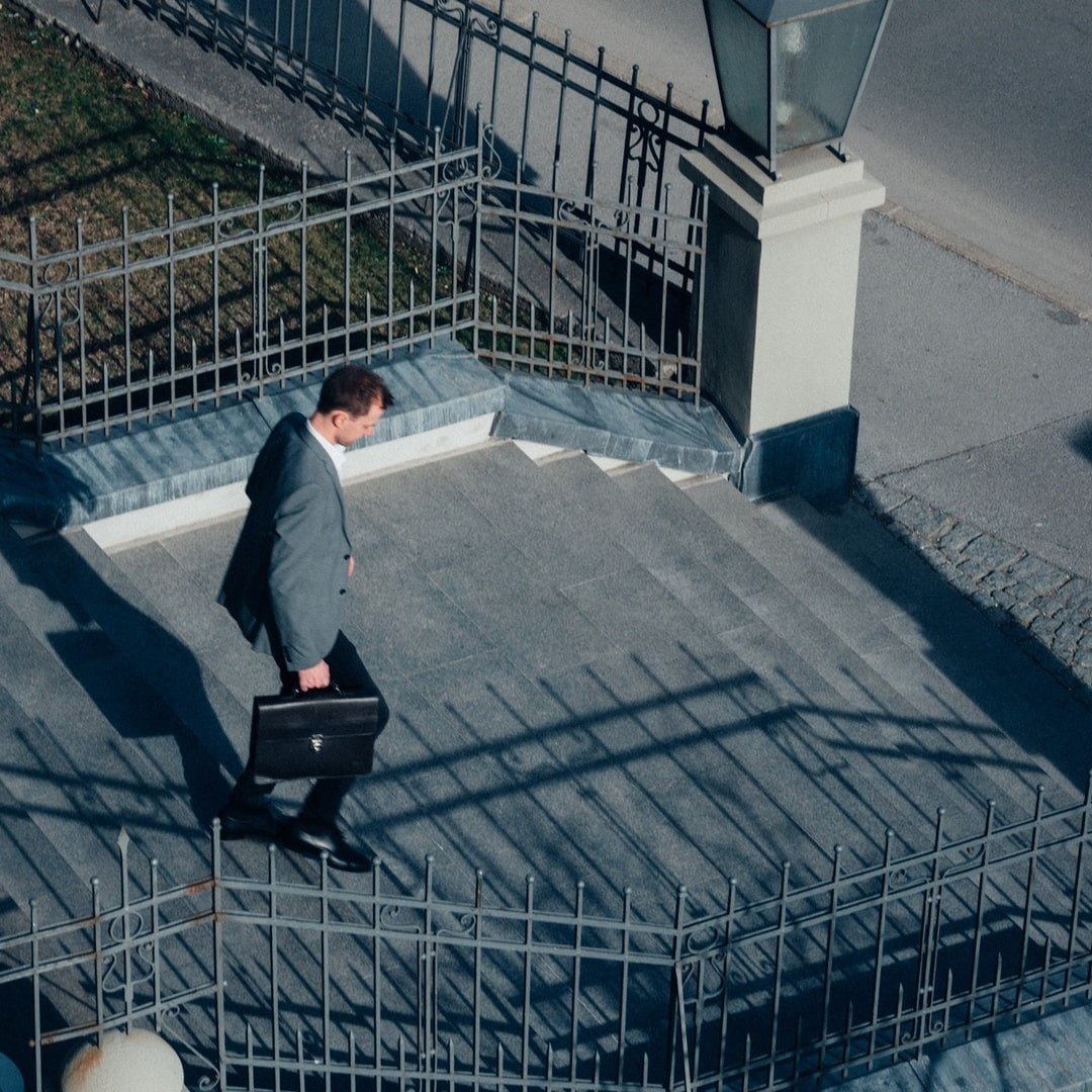 Ein Mann im Anzug geht eine Treppe hinunter, der Schatten fällt auf die Stufen.